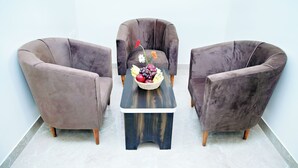 Een kamer met drie fauteuils en een kleine tafel met een fruitschaal.