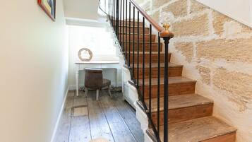 A staircase with wooden steps and a black railing, leading to a landing with a white desk and chair.