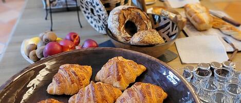 A breakfast table with croissants, bread, and a vase of flowers.