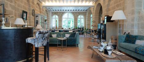 A spacious interior with stone walls, arched windows, and a central seating area with sofas and a coffee table.