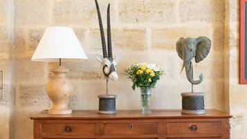 Un aparador de madera con una lámpara, una cabeza de animal decorativa y un florero con flores.