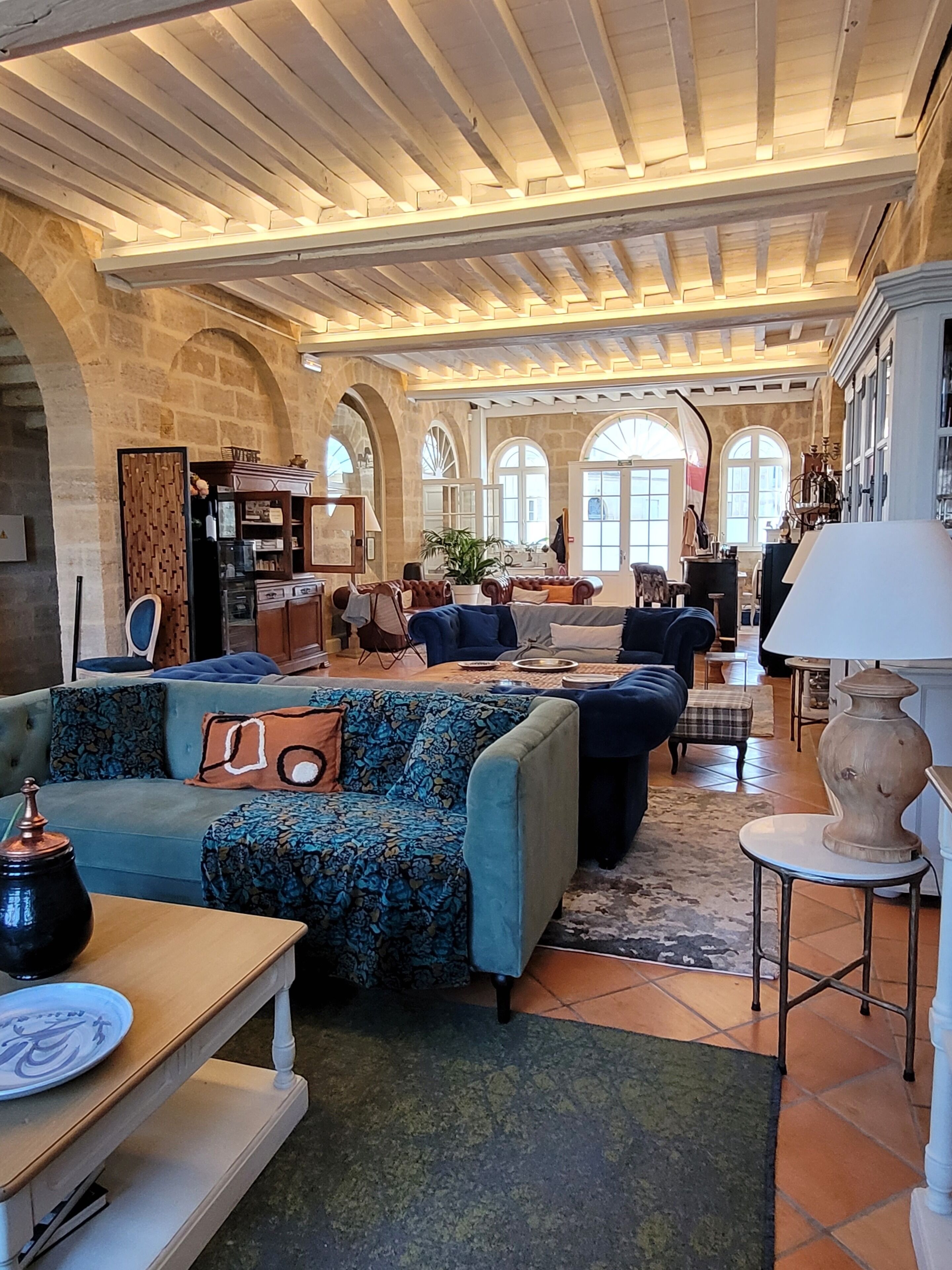 A spacious living area with a high ceiling, stone arches, and a mix of sofas and armchairs.
