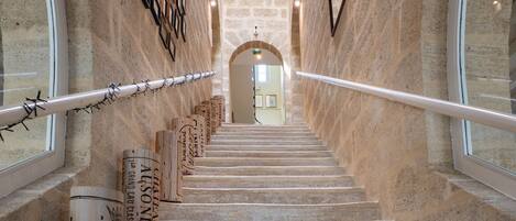 A stone staircase leading to a room with a window, surrounded by stone walls and a railing.