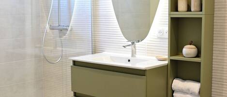 A modern bathroom with a shower, vanity, and storage shelves.