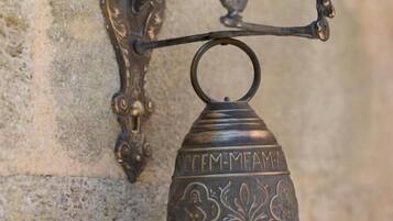 A wall-mounted metal bell with intricate designs and the inscription "TEM-MEM-MA".