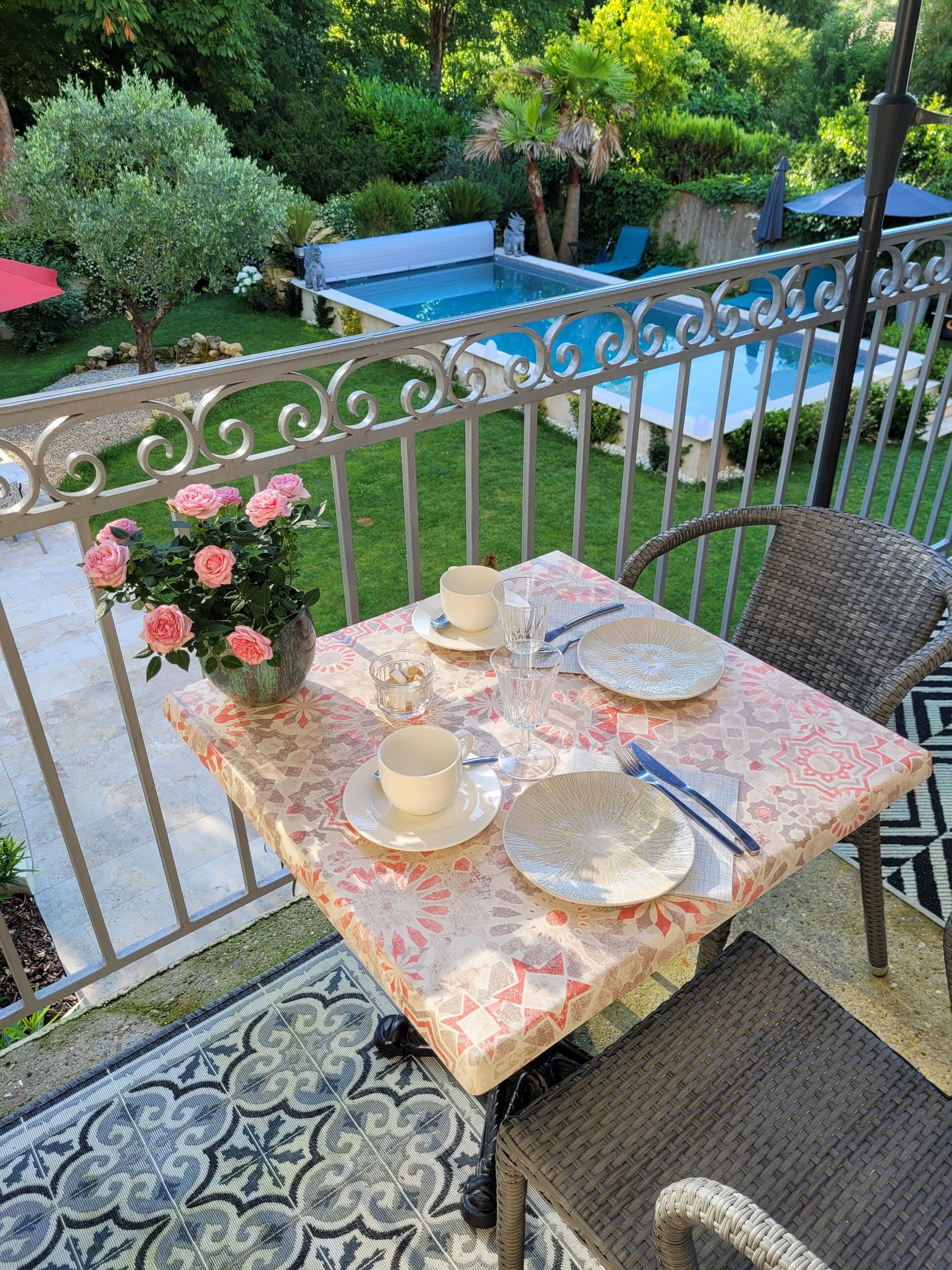 Mesa de comedor al aire libre con vista a una piscina al fondo.