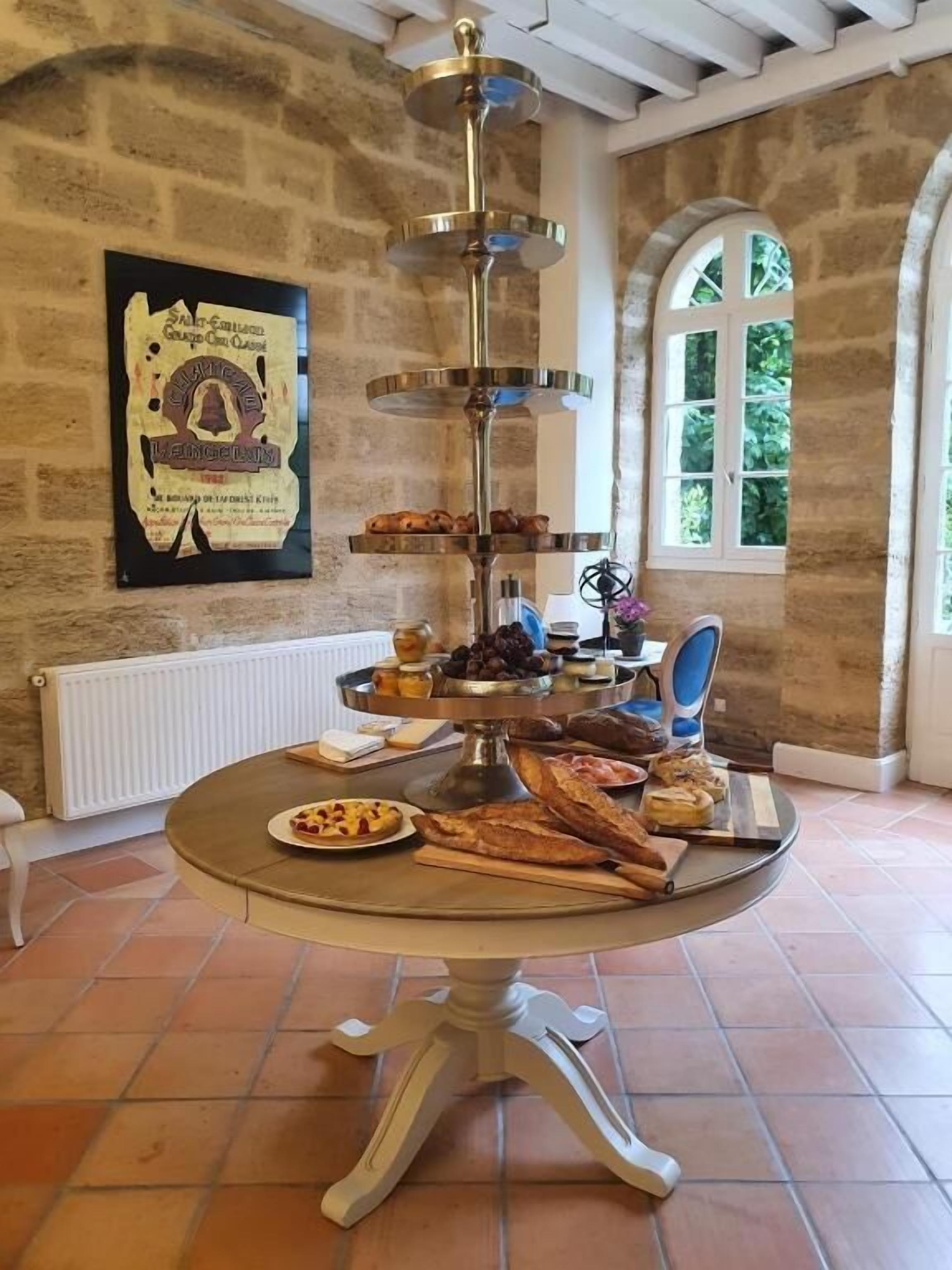 A round table with a tiered serving tray in a room with stone walls and a window.