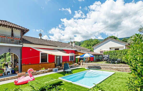 A red house with a swimming pool, a patio with outdoor furniture, and a flamingo float. - Cozy home in Sessa Cilento (Sessa Cilento)