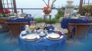 An outdoor dining area with tables set for breakfast, overlooking a body of water. - B&B La Guardia  (Anacapri)
