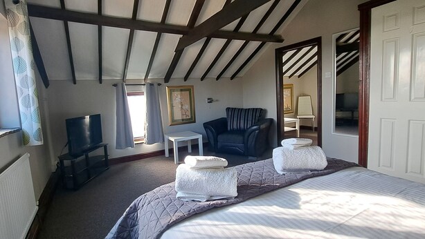 A bedroom with a bed, a chair, a TV, and a small table.