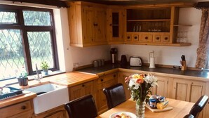 A wooden kitchen with a wooden table, chairs, a sink, and cabinets.