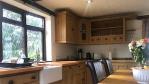 A kitchen with wooden cabinets, a sink, a stove, and a dining table.