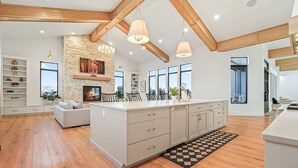 Un'ampia cucina con un'isola grande, travi in legno e un camino.