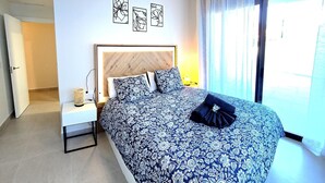 A bedroom with a bed, nightstand, and wall art. - Luxury 2-Bedroom Apt with Jacuzzi, Patio & Parking 1km from Beach (Torremolinos)