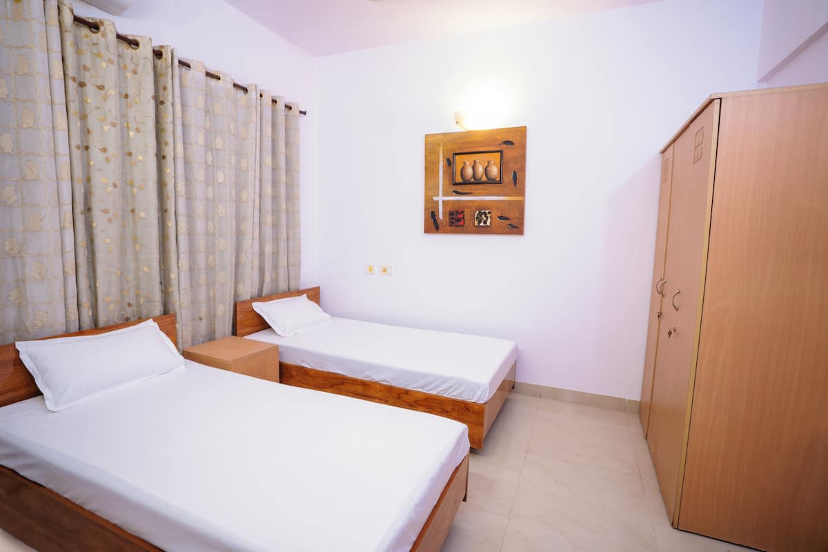 Una habitación con dos camas de madera, un armario y una lámpara fijada a la pared.