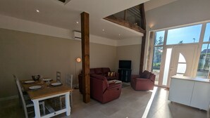 A spacious living area with a dining table set for four, a sofa, and a television. - Charming renovated house in the heart of Loire Valley with parking and wifi (Chaingy)