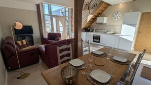 A modern living room with a sofa, a dining table set with plates and glasses, and a kitchen in the background. - Charming renovated house in the heart of Loire Valley with parking and wifi (Chaingy)