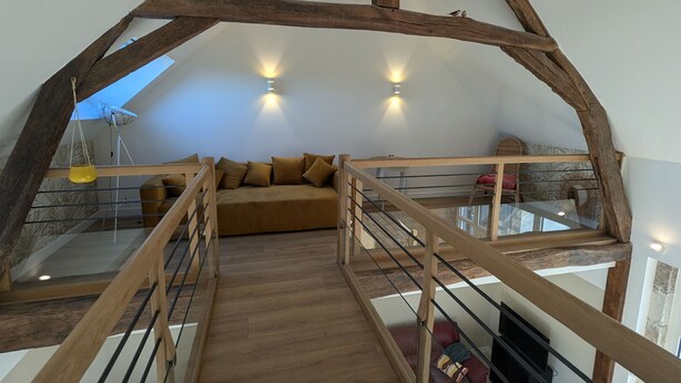 A loft-style room with a wooden staircase, a sofa, and a glass railing. - Charming renovated house in the heart of Loire Valley with parking and wifi (Chaingy)