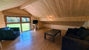 Een ruime loft met houten vloeren, een groot raam, een flatscreen-tv en een gezellige zithoek.