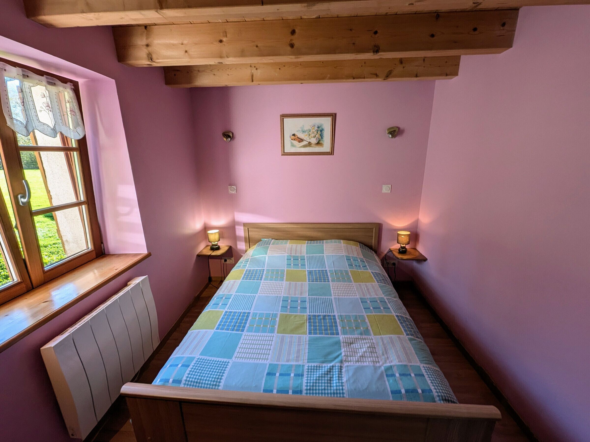 A bedroom with a wooden bed, a window with a view, and two bedside lamps.