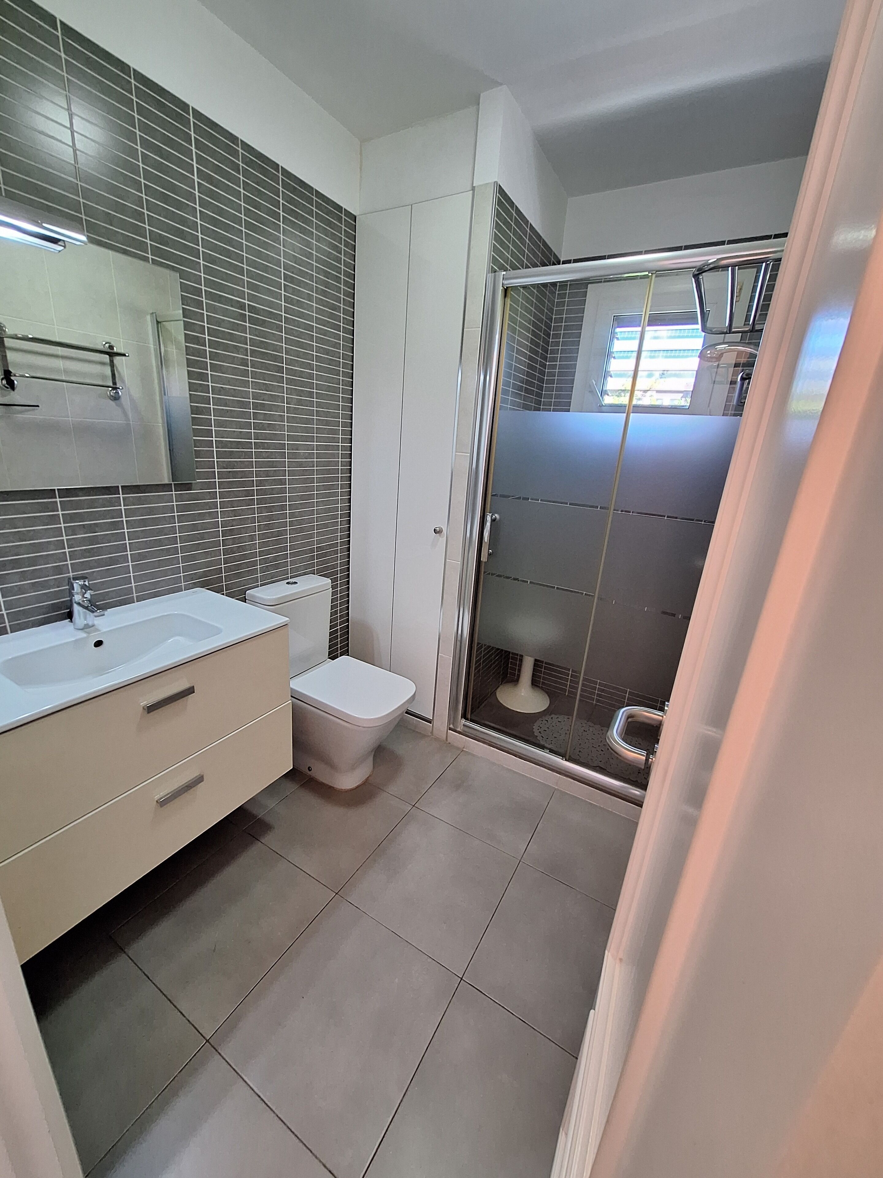 Un baño moderno con un tocador blanco, un inodoro y un box de ducha de vidrio.