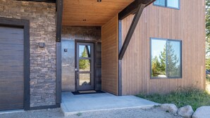 A modern building with a stone facade, a wooden entrance, and large windows. - The Basin is a modern, luxury cabin nestled in the pines at the base of Discovery Ski Hill. Enjoy panoramic views of the surrounding forest and the relaxing sounds of a nearby creek while relaxing by a smokeless fire in the Solo stove on the deck. (Philipsburg)