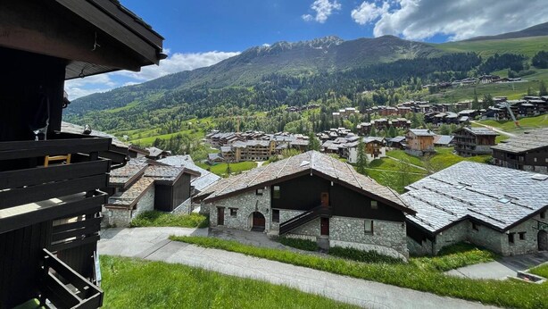 A mountain village with stone buildings and a view of the surrounding mountains.