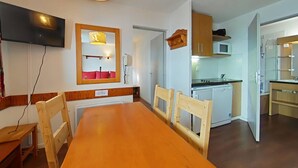 A modern kitchen with a microwave, stove, and wooden cabinets. - Apartment 5 pers, parking, Plagne Soleil (Plagne Soleil)