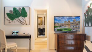 Ein Hotelzimmer mit Schreibtisch, Stuhl, Fernseher und Bildern an den Wänden.