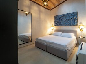 A modern bedroom with a large bed, a mirror, and wall-mounted lights. - Casa Philomena - Noto Design Rooms (Noto)