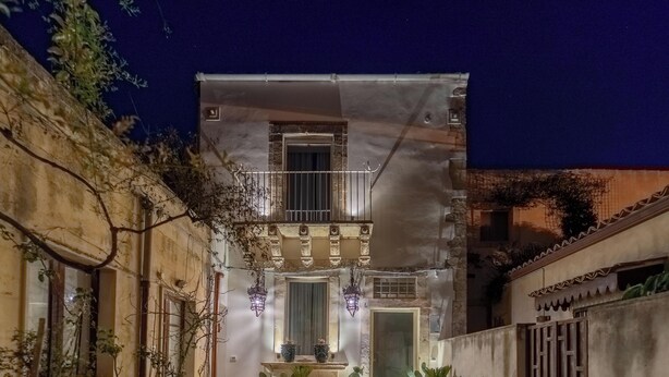 Ein Gebäude mit einem Balkon, einer Tür und zwei hängenden Laternen.
