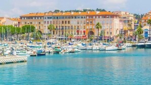 Ein Yachthafen mit vertäuten Booten, eine Uferpromenade und Gebäude mit orangefarbenen Dächern.