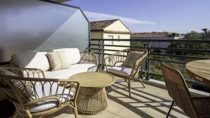 Ein Balkon mit Korbmöbeln, einem runden Tisch und einer Hängelampe.