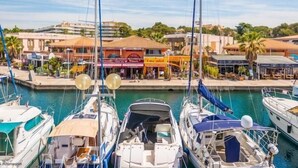 Ein Yachthafen mit mehreren angedockten Booten, einem Restaurant am Wasser und einem Gebäude mit rotem Markisenvorzelt.