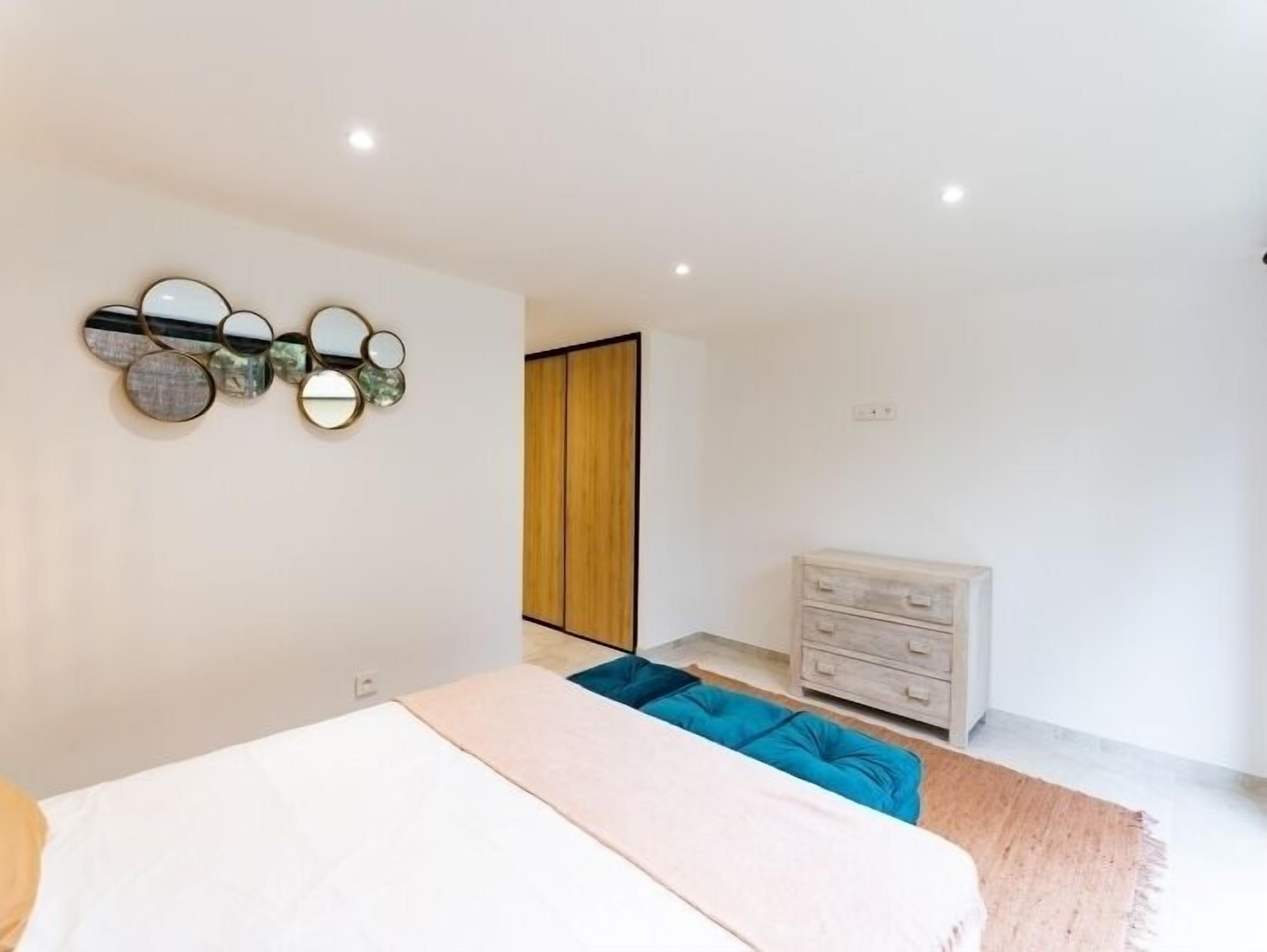A modern bedroom with a bed, a dresser, and a wall-mounted mirror.