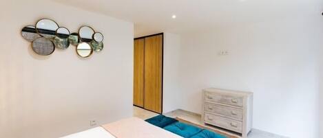A modern bedroom with a bed, a dresser, and a wall-mounted mirror.