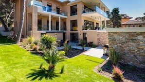A modern two-story house with a spacious patio, a stone wall, and a well-maintained lawn. - Appart Hotel | 3 bedrooms | Parking | swimming pool (Saint Raphaël)