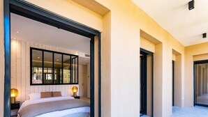 A modern bedroom with a large bed, two bedside lamps, and a large mirror above the bed. - Appart Hotel | 4 rooms | Parking | swimming pool (Saint Raphaël)