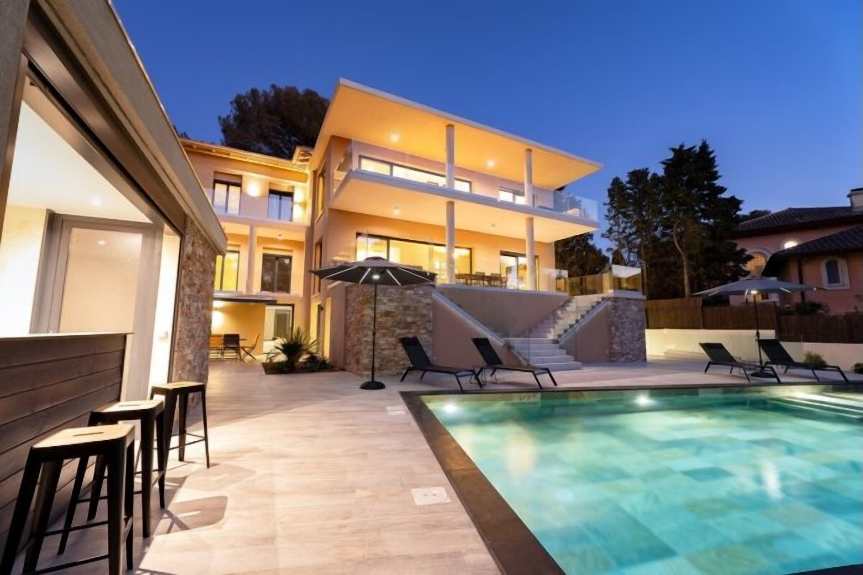 A modern two-story house with a swimming pool, outdoor seating, and a staircase leading to the upper level.