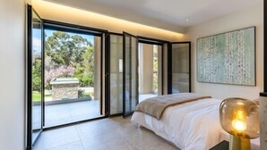 A bedroom with a large sliding glass door leading to a balcony, a bed with a white duvet, and a modern floor lamp. - Appart Hotel | 4 rooms | Parking | swimming pool (Saint Raphaël)