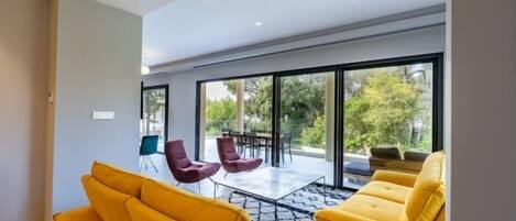 A modern living room with yellow sofas, a coffee table, and a dining area with chairs and a table.
