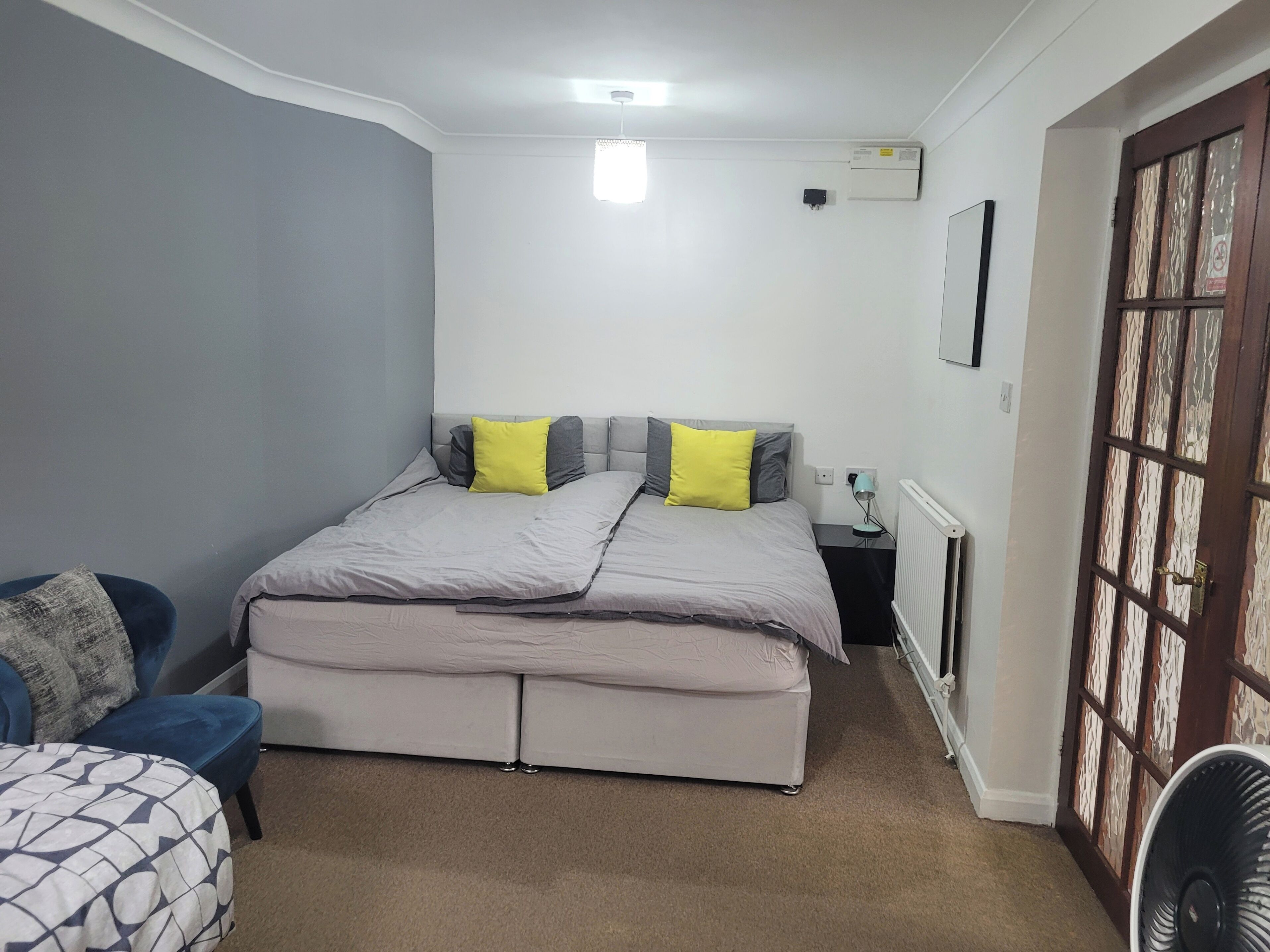 A bedroom with a bed, bedside table, lamp, and a radiator.