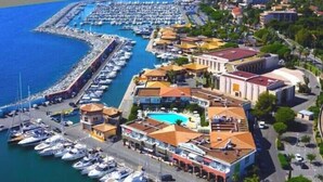 A marina with boats docked, a swimming pool, and buildings with Mediterranean architecture.