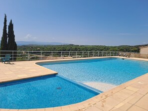Una piscina rectangular con un bordeado de azulejos, rodeada por una barandilla blanca.