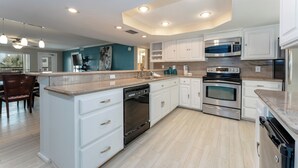Una cocina moderna con armarios blancos, electrodomésticos de acero inoxidable y una isla central.