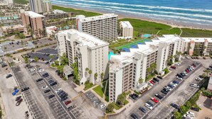 Un hotel moderno de muchas plantas, con estacionamiento y vistas a la playa y al océano.
