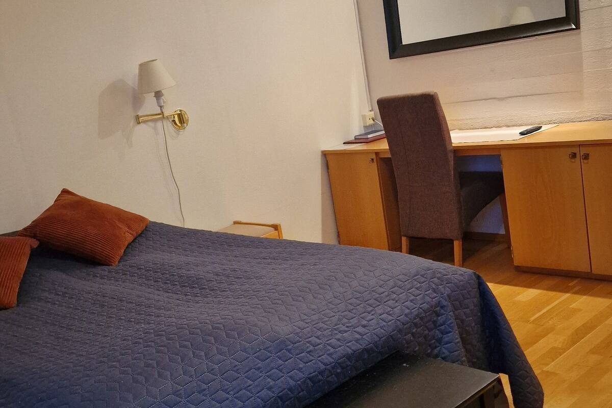 Ein Schlafzimmer mit Bett, Schreibtisch und Stuhl.