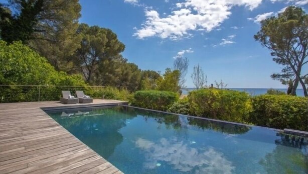 A wooden deck with a clear blue pool, surrounded by greenery and overlooking a body of water. - Villa 8 pers | waterfront | 180° sea view (.Saint-Raphaël)