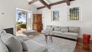A spacious living room with a grey sofa, a wooden coffee table, and a white rug. There are two windows with bars, a wooden cabinet, and a door leading outside. - Villa 8 pers | waterfront | 180° sea view (.Saint-Raphaël)