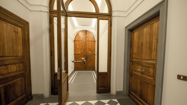 Un pasillo con puertas de madera y piso a cuadros.